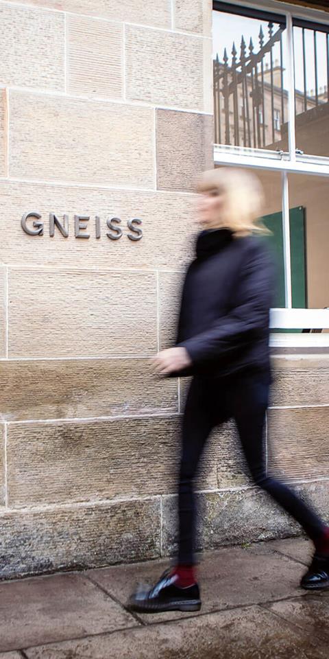 A person walking towards the entrance door of Gneiss Energy's office.